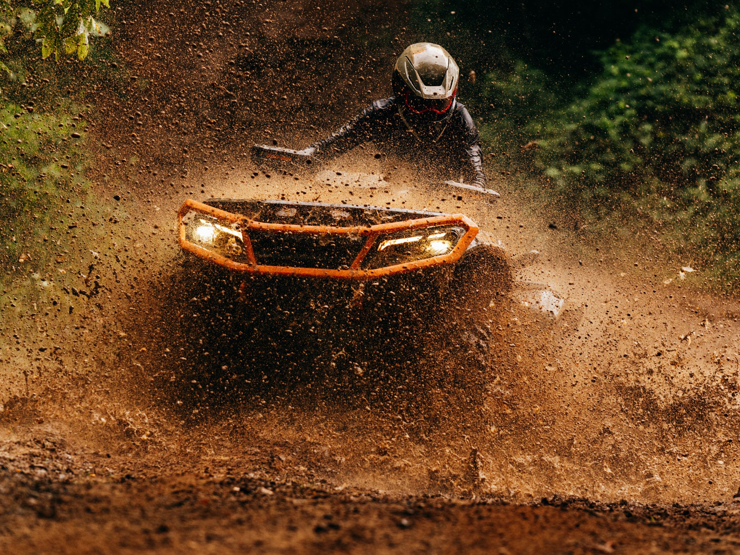 Mies ajaa Can-Am Outlander -mönkijällä seisaallaan syvässä mudassa